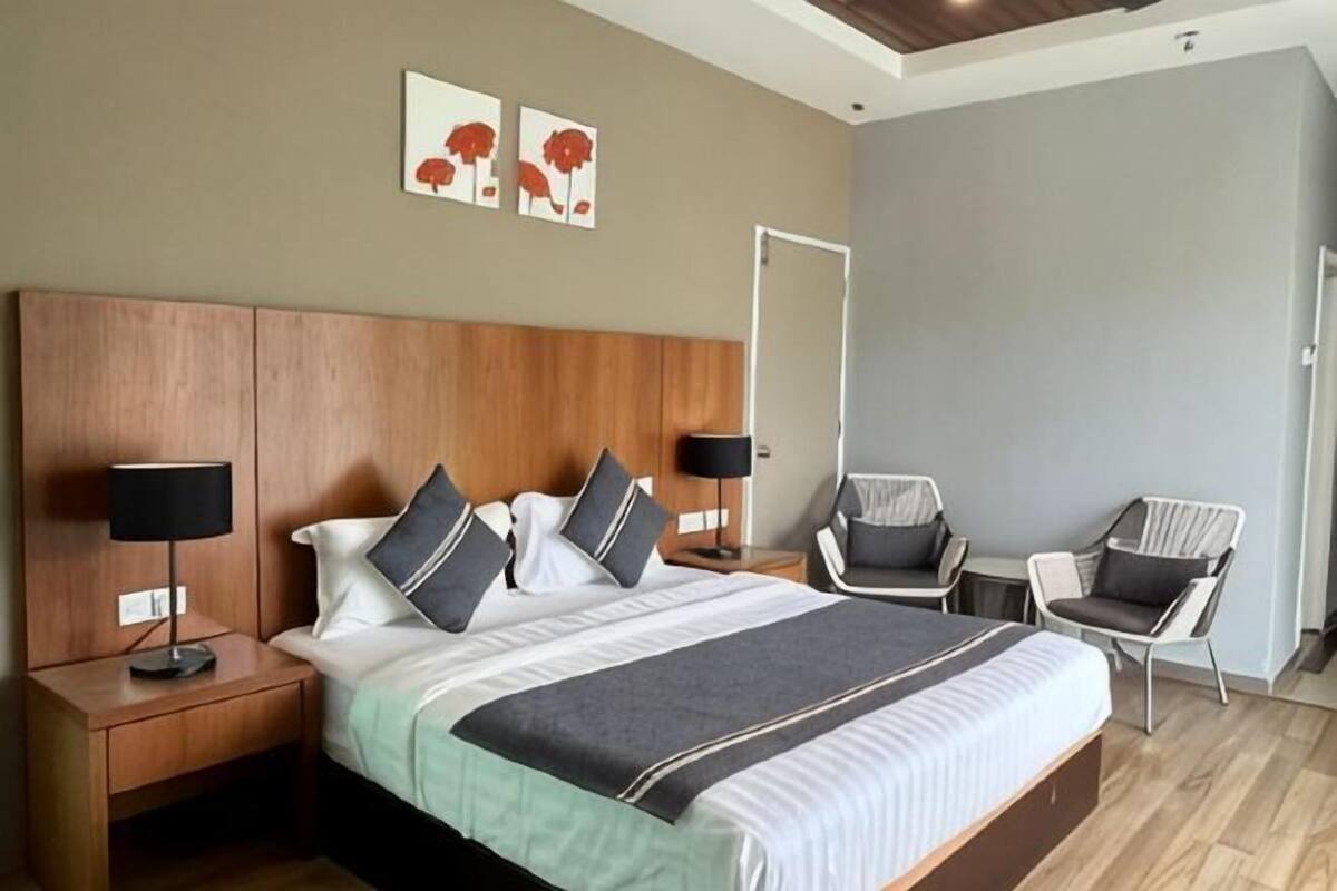 A hotel room with a large bed, two bedside tables with lamps, a chair, and artwork on the wall.
