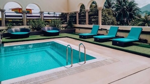 Una piscina con sillas de descanso y un pequeño jacuzzi.
