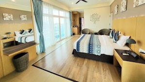 Una habitación de hotel moderna con una cama grande, una zona de estar con dos sillones, una mesita y un ventilador de techo.