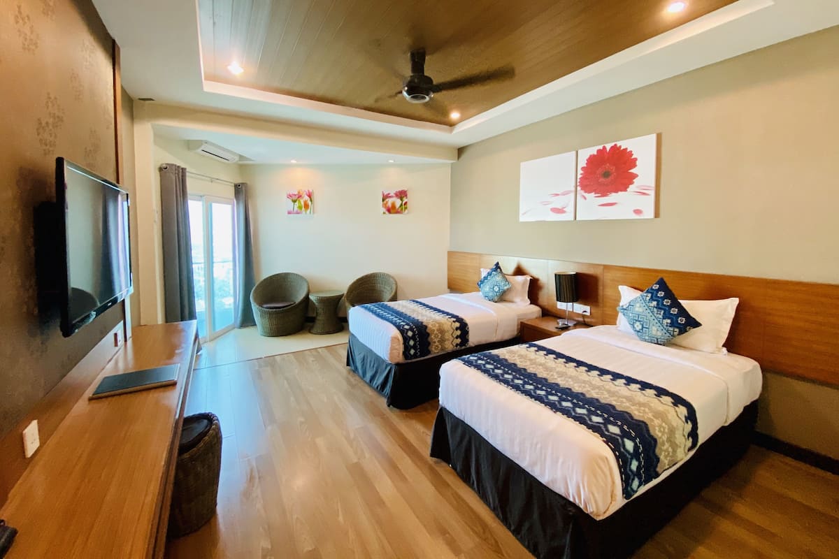 A hotel room with two beds, a TV, a ceiling fan, and a large window.