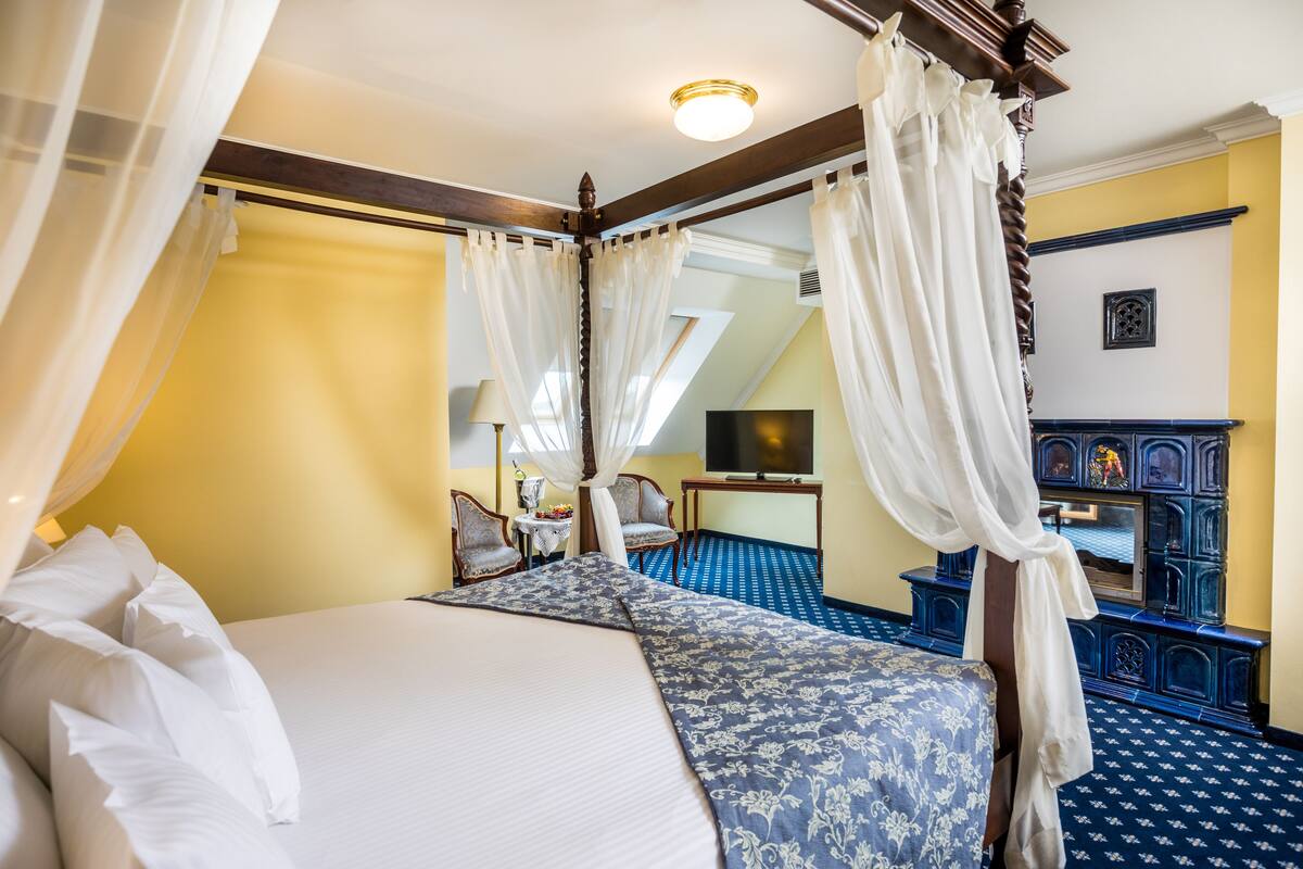 A bedroom with a four-poster bed, a television, and a small table with chairs.
