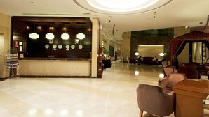 A spacious lobby with a reception desk, multiple seating areas, and a large chandelier. - Grand Belle Vue (Dubai)
