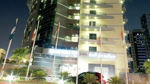 A high-rise hotel with multiple floors, balconies, and a well-lit facade. - Grand Belle Vue (Dubai)