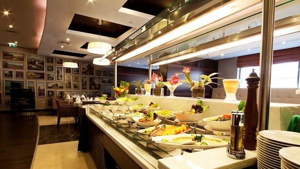 A buffet area with various dishes and a glass display case. - Grand Belle Vue (Dubai)