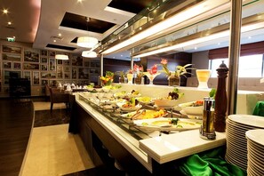 A buffet area with various dishes and a glass display case. - Grand Belle Vue (Dubai)
