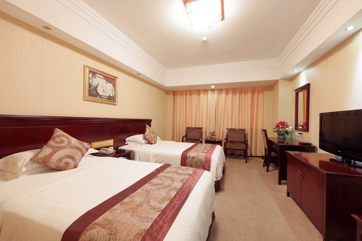 Une chambre d’hôtel avec deux lits, une télévision, un bureau et une chaise.