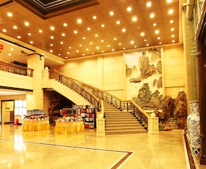 Un espacio interior amplio con una escalera, estanterías y un mural decorativo.