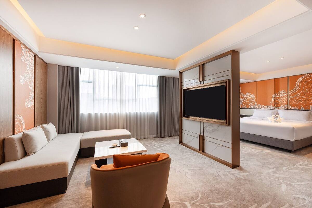 Une chambre d’hôtel moderne équipée d’un canapé, d’une table à manger, d’un téléviseur et d’un lit.