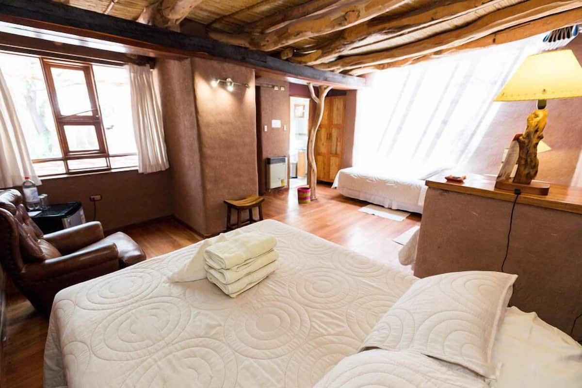 A cozy room with a large bed, a wooden desk, a chair, and a lamp.