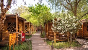 A wooden pathway leading to rustic cabins with a sign indicating room availability. - Hotel Kimal (San Pedro de Atacama)