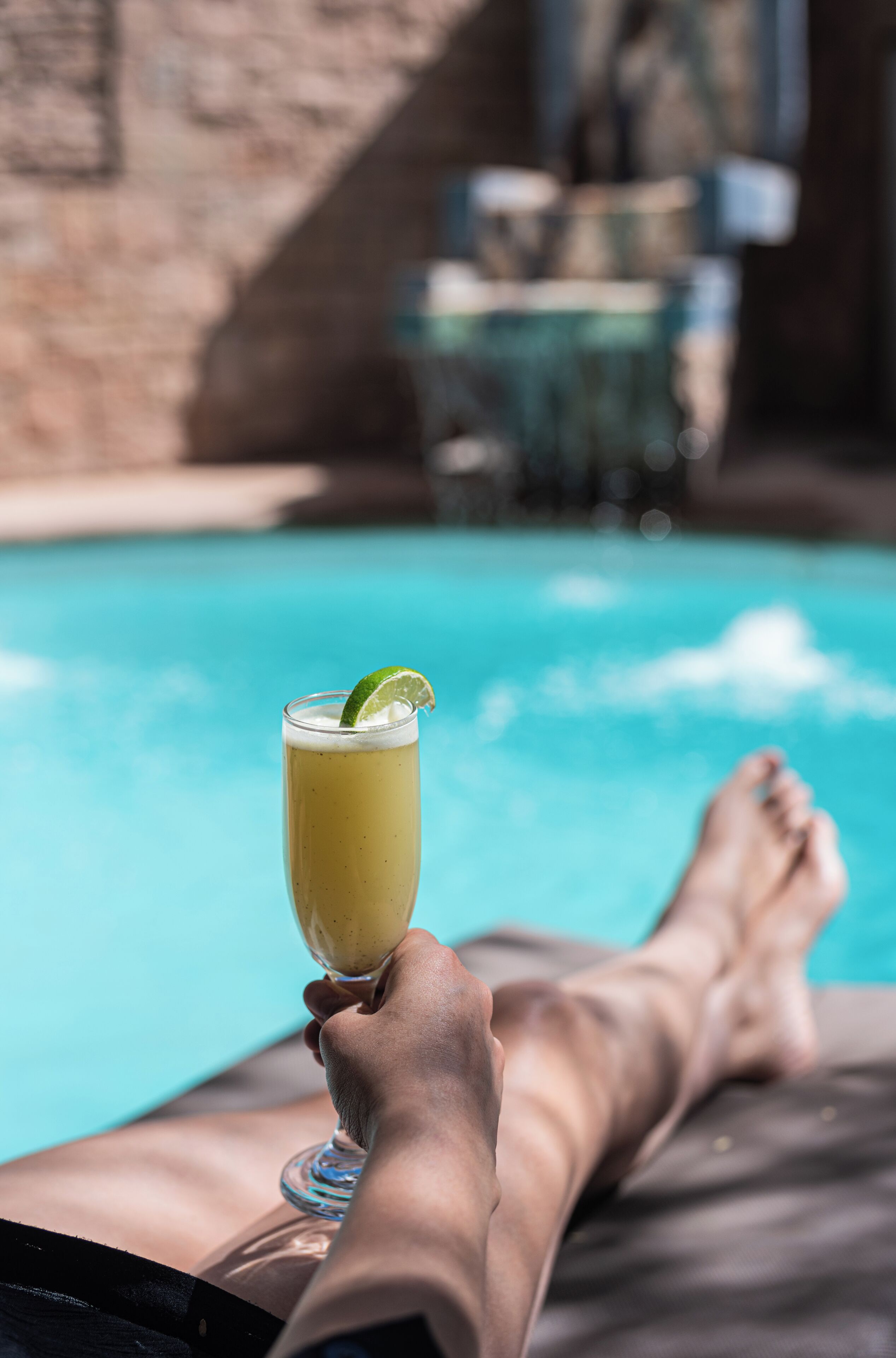 Eine Person entspannt am Pool mit einem Getränk in der Hand.