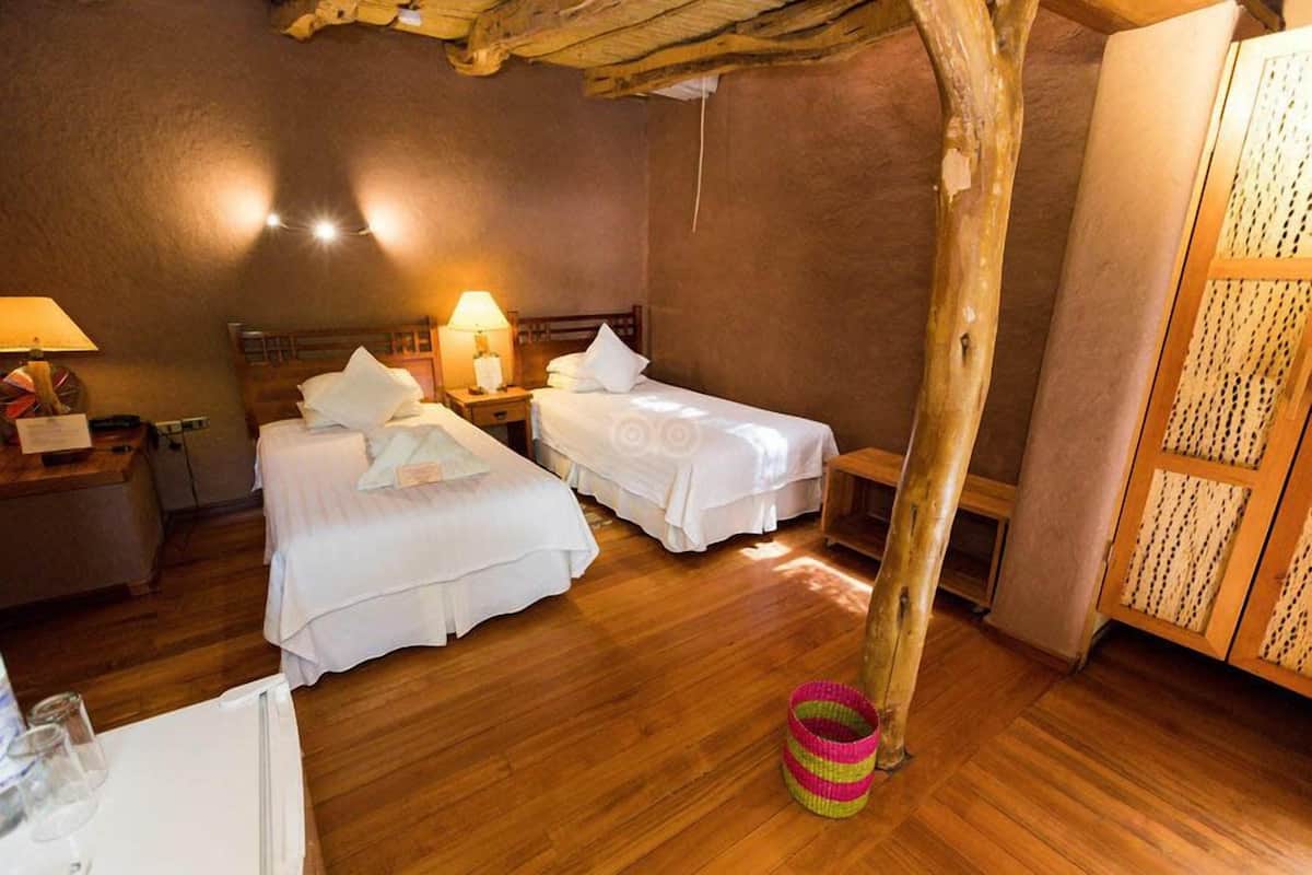 A cozy room with two beds, wooden floors, and a rustic ceiling.