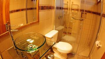 Un baño moderno con lavamanos de vidrio, inodoro y ducha con cerramiento de vidrio.