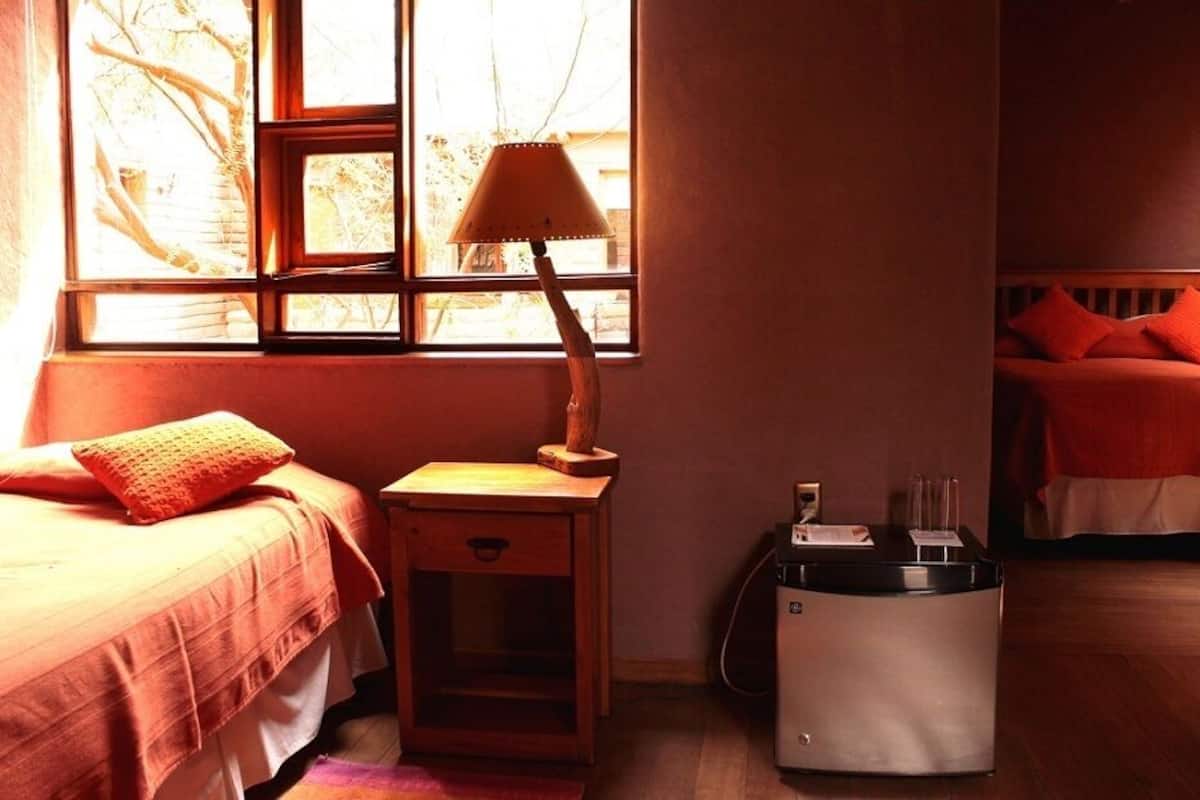 A bedroom with a bed, a nightstand, a lamp, and a heater.