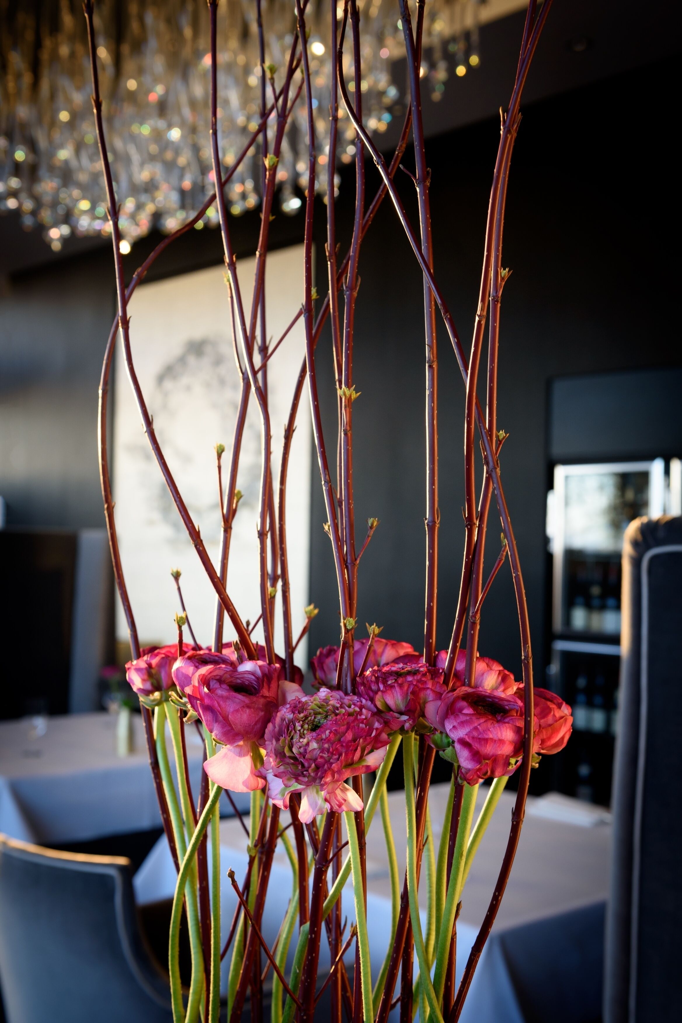 A modern interior with a dining area, a chandelier, and a view of a cityscape.