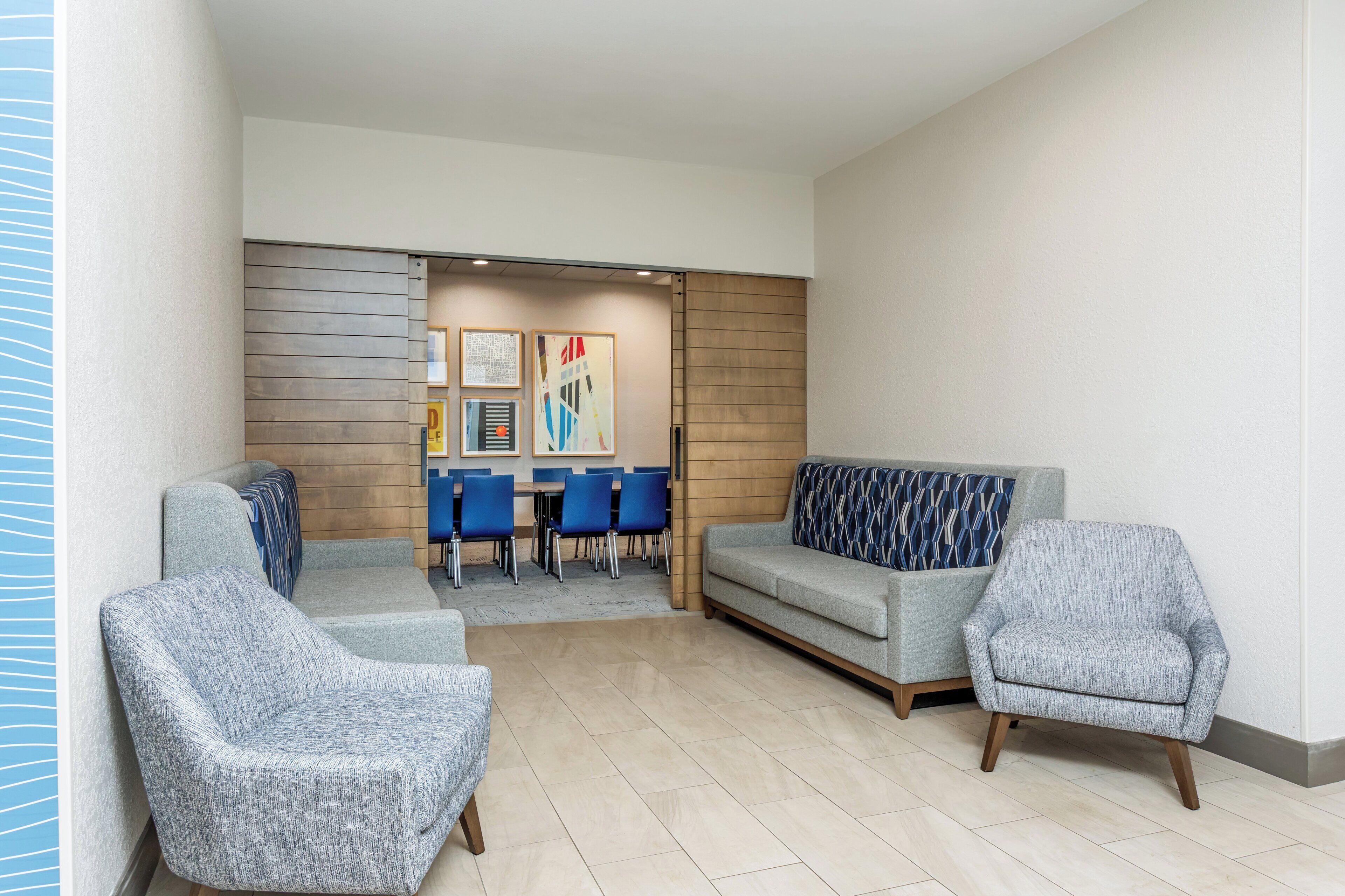 A modern lobby with a seating area, a wooden wall, and a dining setup.