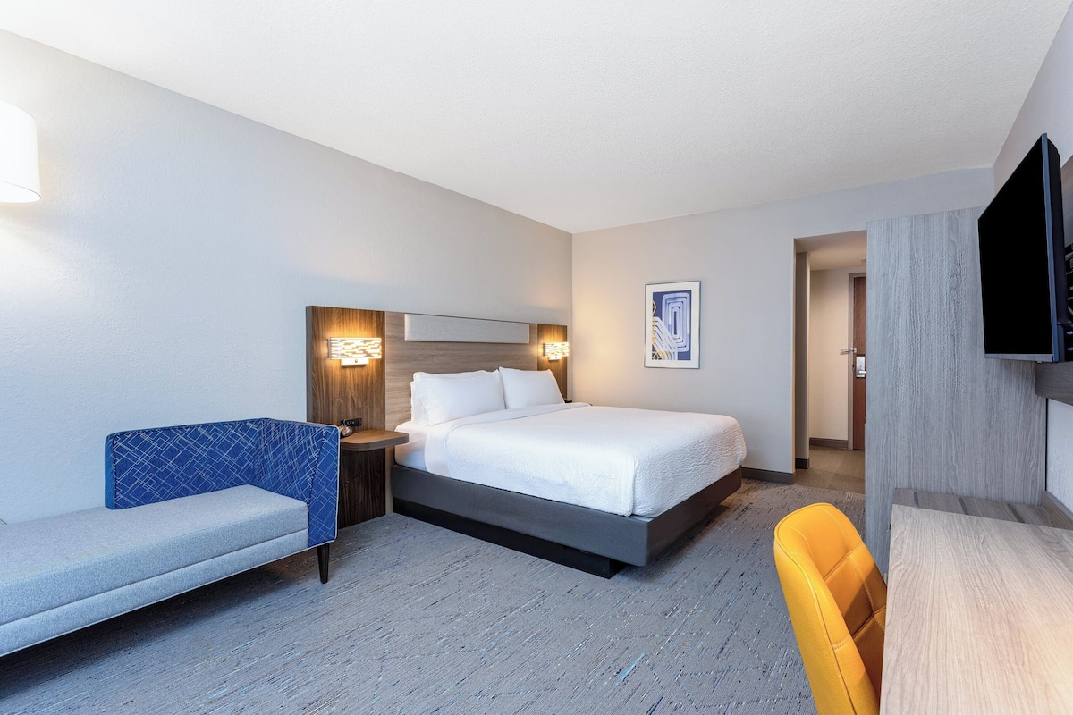 A hotel room with a bed, a sofa, a desk, and a TV.