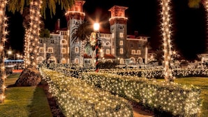 Un edificio histórico con torres iluminadas y un jardín bien cuidado, de noche.