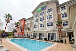 Guests can enjoy a refreshing swim in the hotel's outdoor pool surrounded by a deck and palm trees.