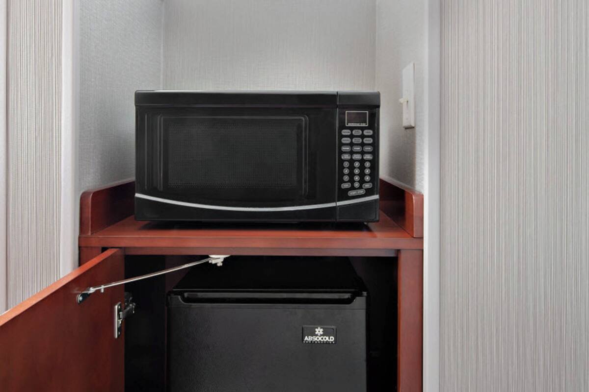 A microwave on a wooden shelf in a kitchen cabinet.