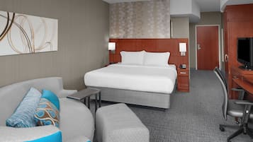Habitación de hotel con una cama grande, un sofá, un escritorio y un televisor.