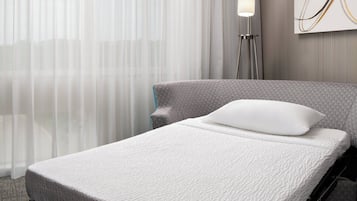 Una cama bien hecha con una almohada blanca y un cabecero gris en una habitación de hotel.