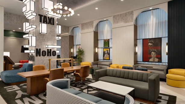 A modern lobby with a central seating area, a reception desk, and a large wall with 'TAXI' and 'NoHo' signage. - DoubleTree by Hilton New York Downtown (New York)