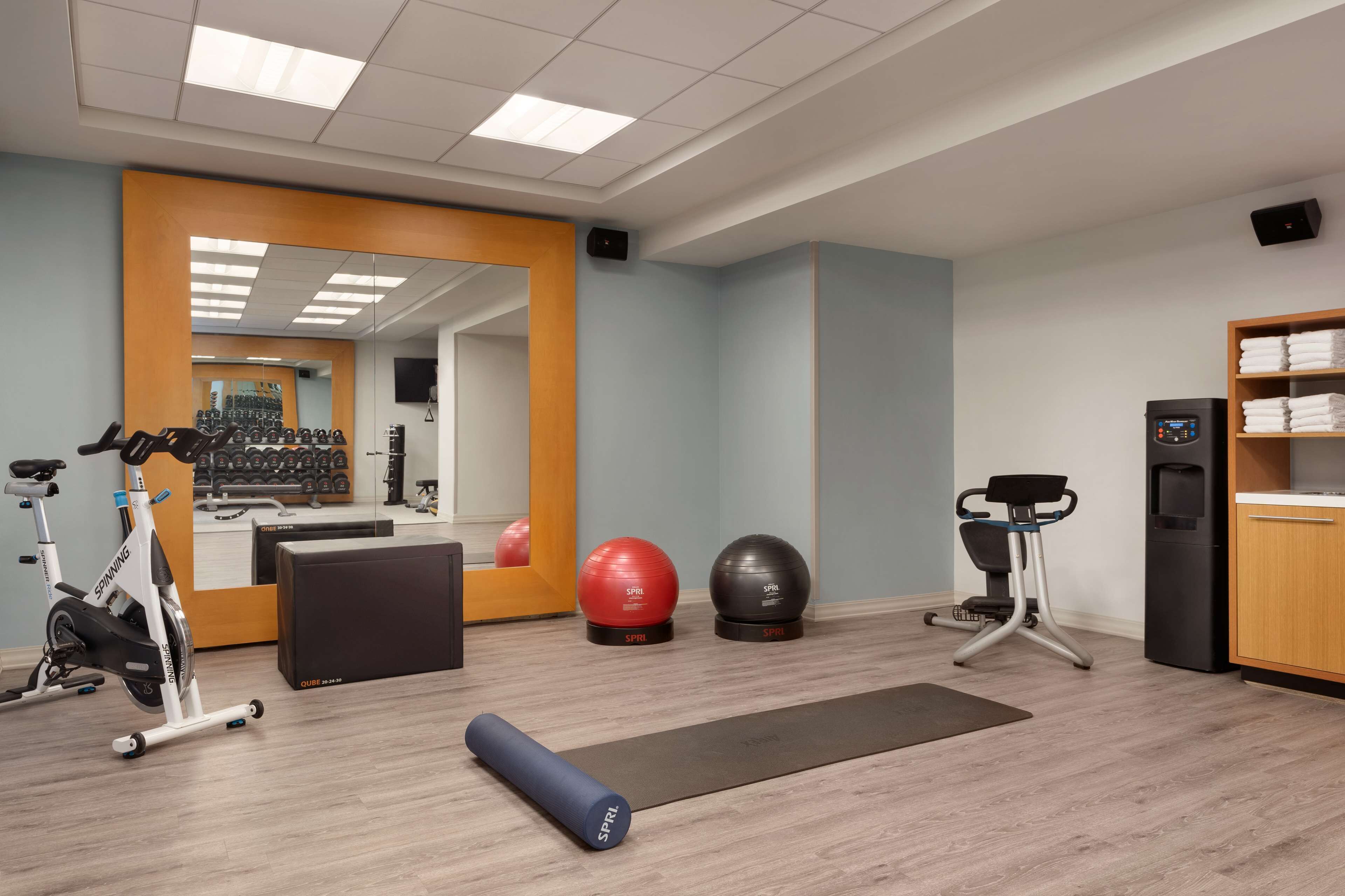 Een sportschool met trainingsapparatuur, een spiegel en een waterdispenser.
