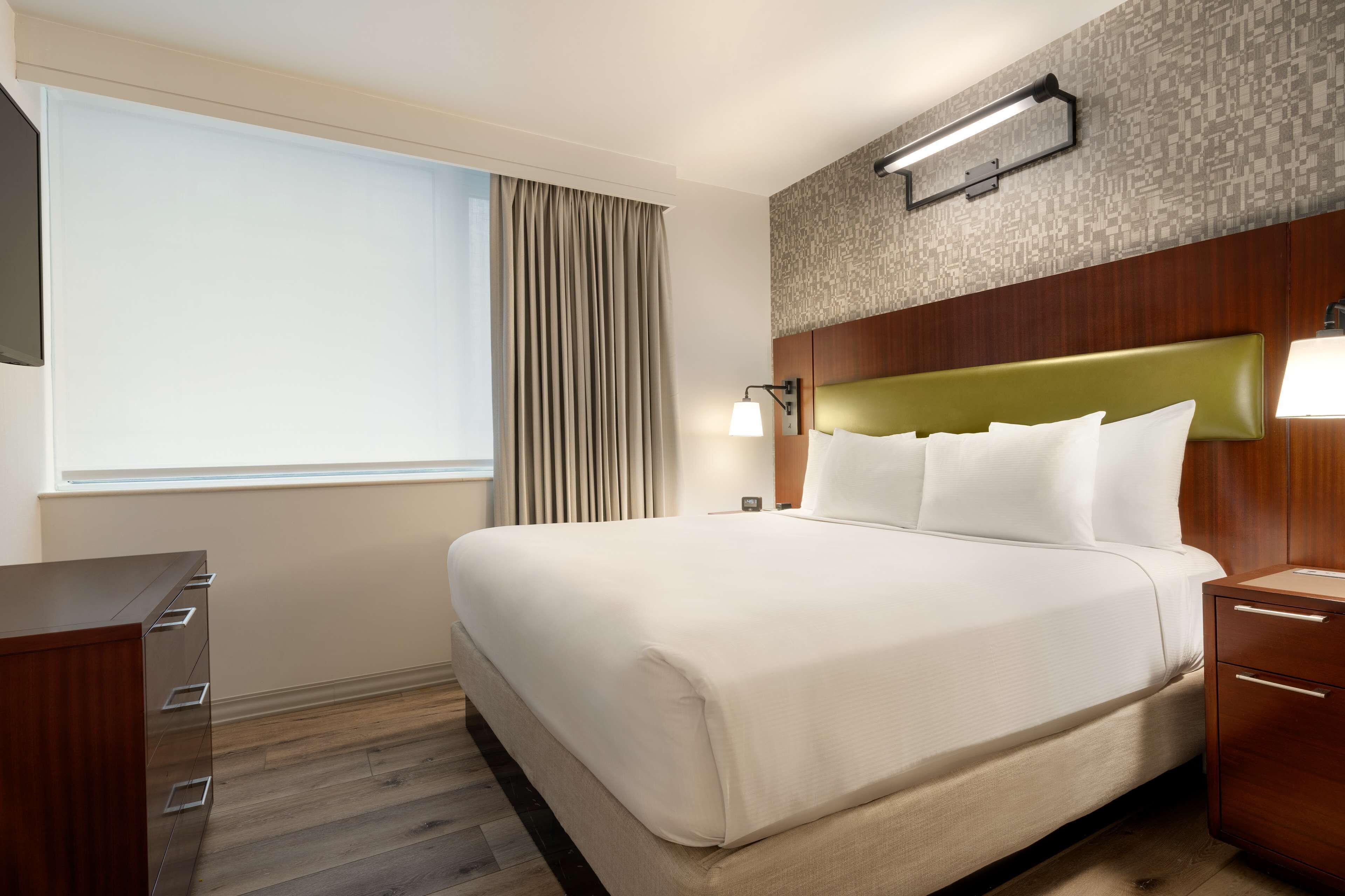 Una habitación de hotel con una cama grande, un escritorio y una mesita de noche.
