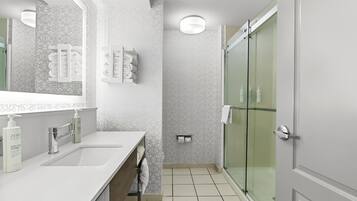 Un bagno moderno con un mobile lavabo doppio, una cabina doccia in vetro e un portasciugamani con asciugamani piegati con cura.