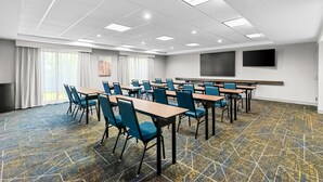 A conference room with tables and chairs, a large screen, and a patterned floor.