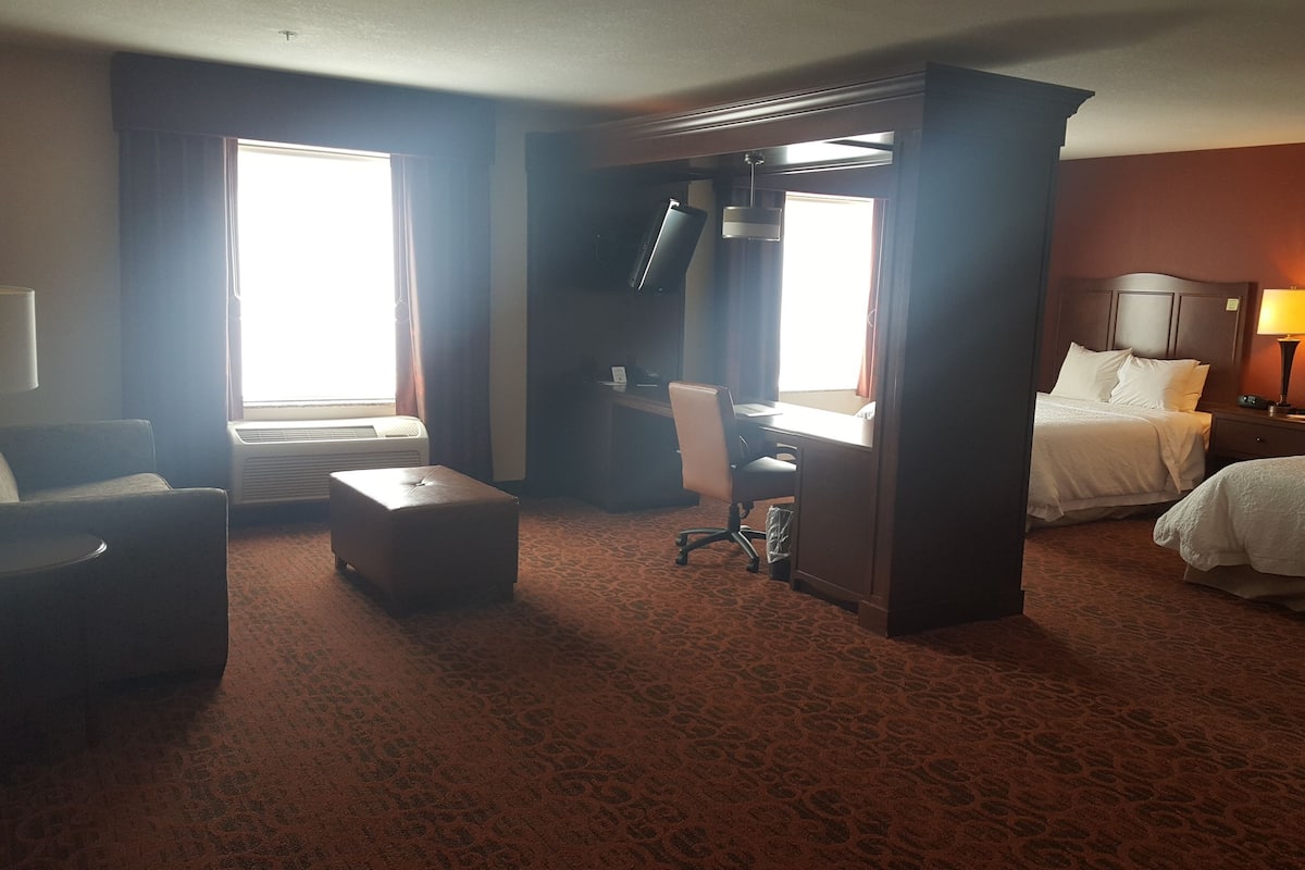 A hotel room with a bed, a desk, a chair, and a sofa.