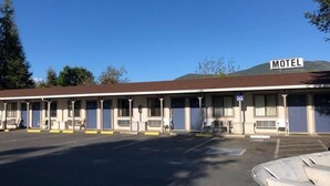 Um motel com uma fileira de quartos, um estacionamento e um sinal indicando acessibilidade para pessoas com deficiência.