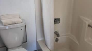 A bathroom with a toilet, a bathtub, and a window.