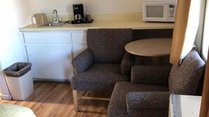 Quarto compacto com cozinha compacta, um sofá e uma pequena mesa.
