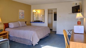 Une chambre d’hôtel avec un lit, un bureau, une chaise, une télévision et un miroir.
