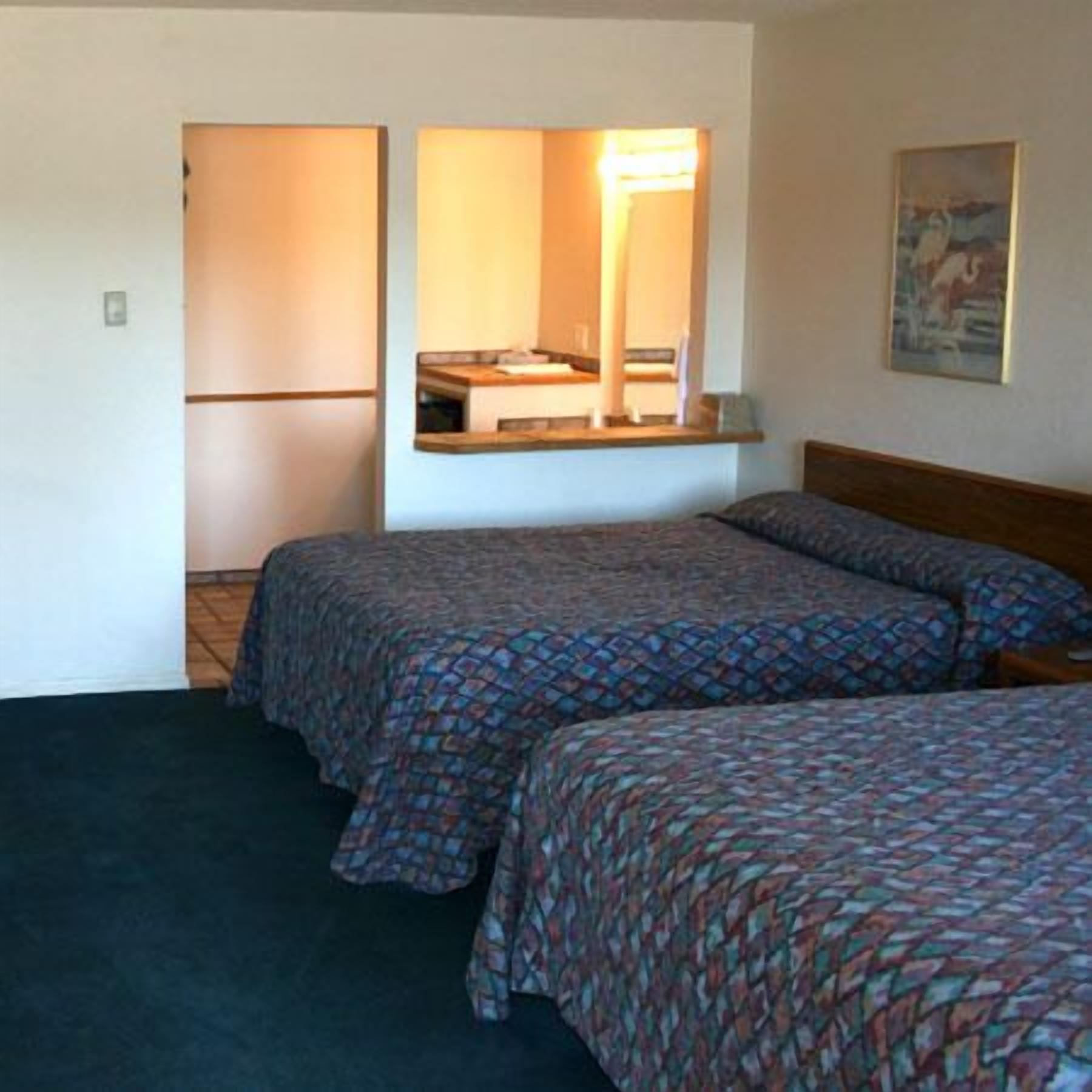 Ett hotellrum med två sängar, ett litet pentry och en tavla på väggen.