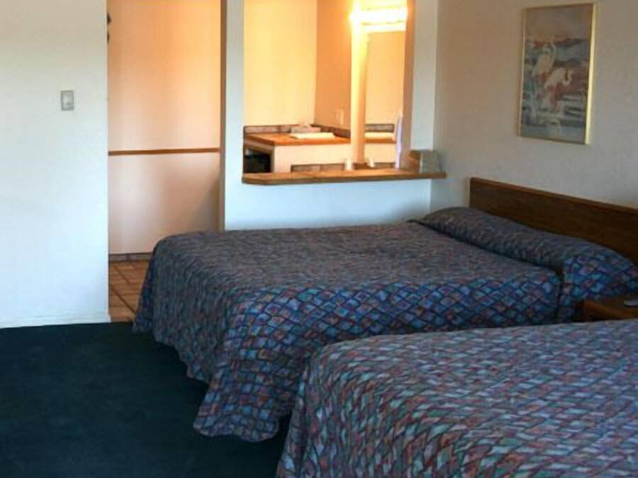 Ett hotellrum med två sängar, ett litet pentry och en tavla på väggen.