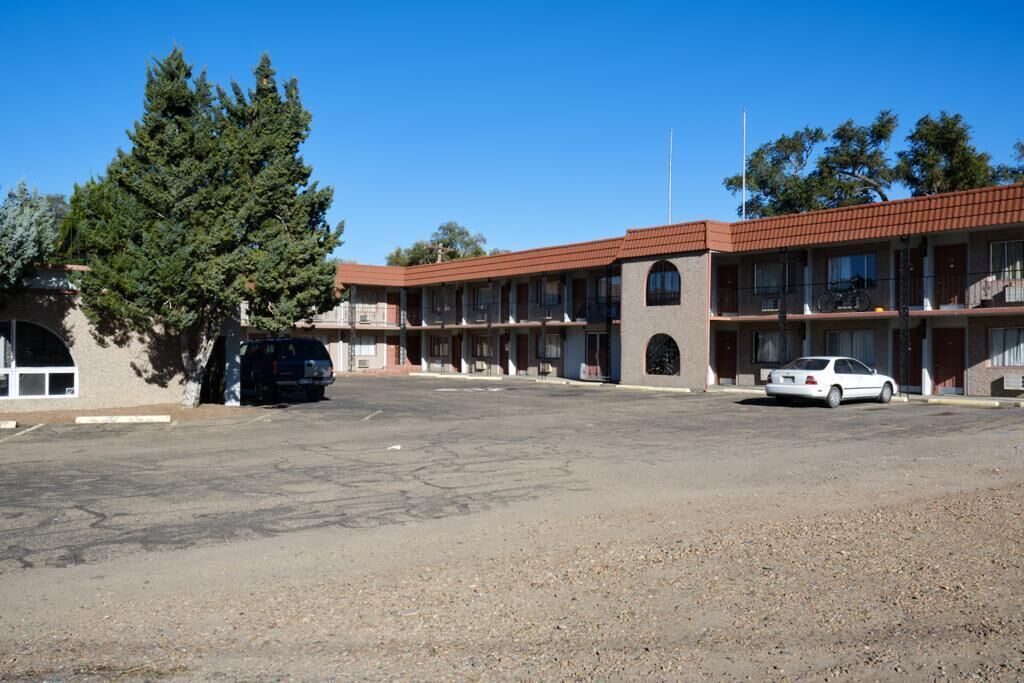 Un motel con un patio central, varios balcones y un estacionamiento.