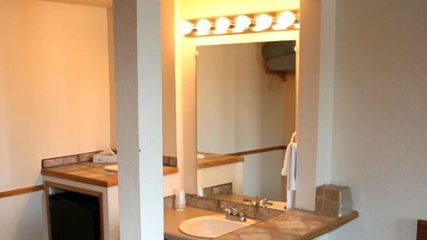Une petite salle de bain avec un lavabo, un miroir et une serviette accrochée au mur.