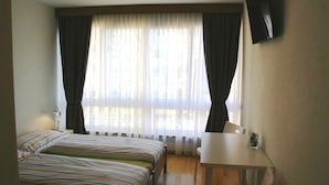 A hotel room with a bed, a desk, and a TV on the wall. - Rovere (Losone)