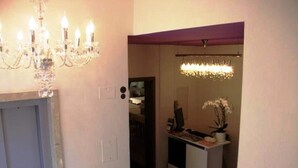 A hallway with a chandelier, a desk with a computer, and a potted plant. - Rovere (Losone)