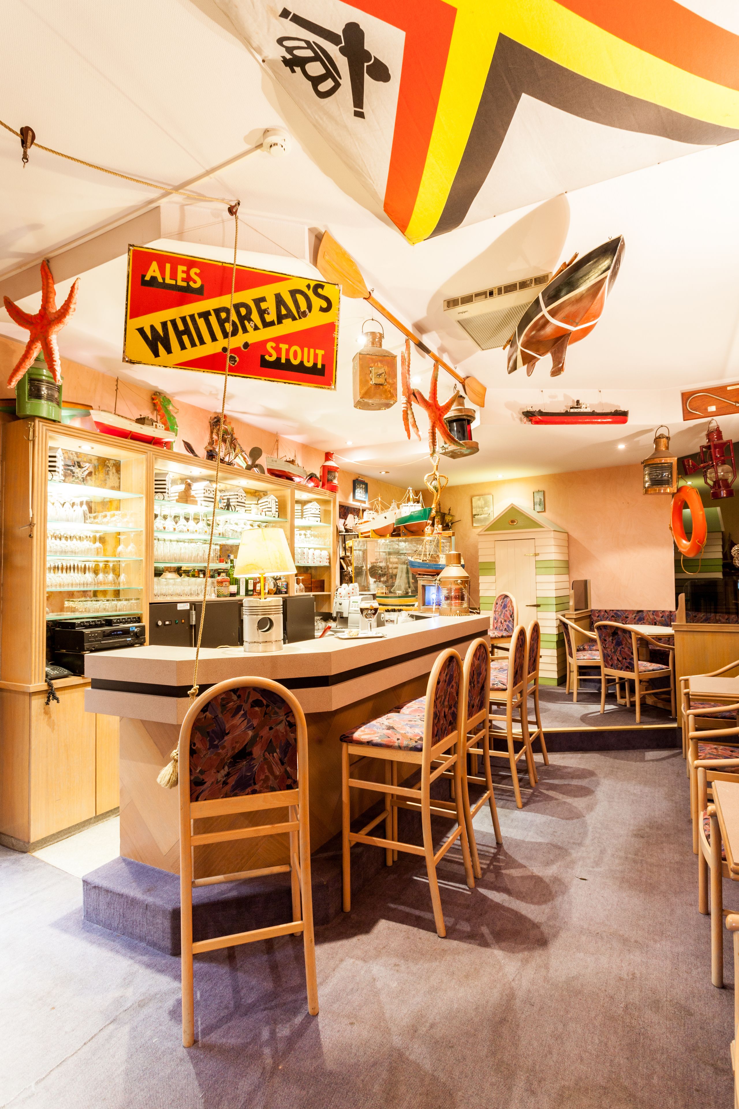 Una zona de bar con mostrador, taburetes y un cartel que anuncia Stout Ales Whitbread's.