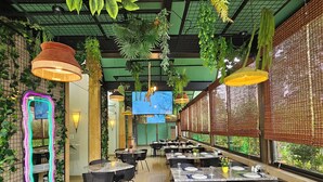 Un restaurant doté de tables à l’intérieur, de plantes suspendues et d’un grand miroir.