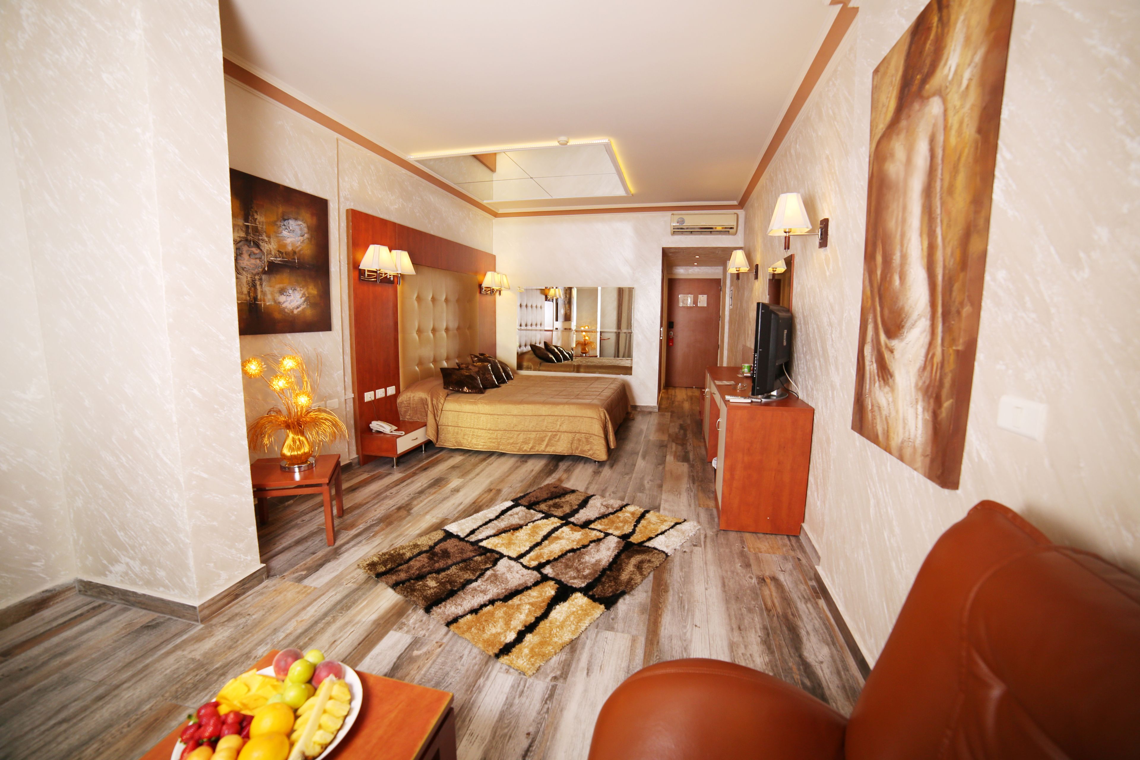 Une chambre d’hôtel équipée d’un lit, d’un canapé, d’une télévision, d’un bureau et d’un panier de fruits.