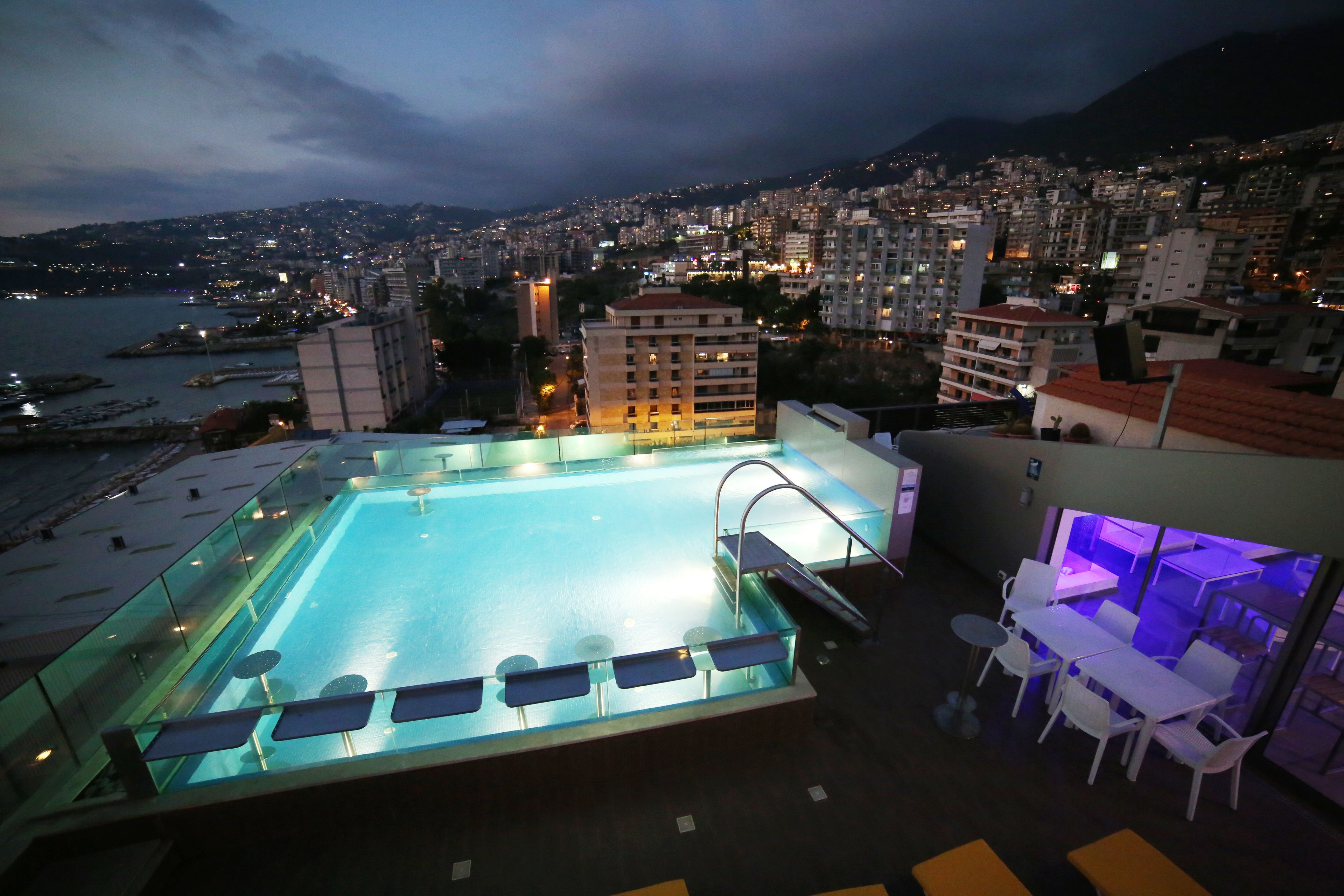 A rooftop pool with a city view, seating area, and a bar/lounge.