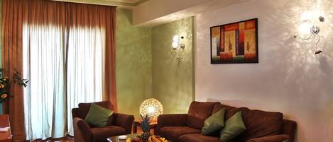 A living room with brown sofas, a coffee table with fruit, and a painting on the wall.