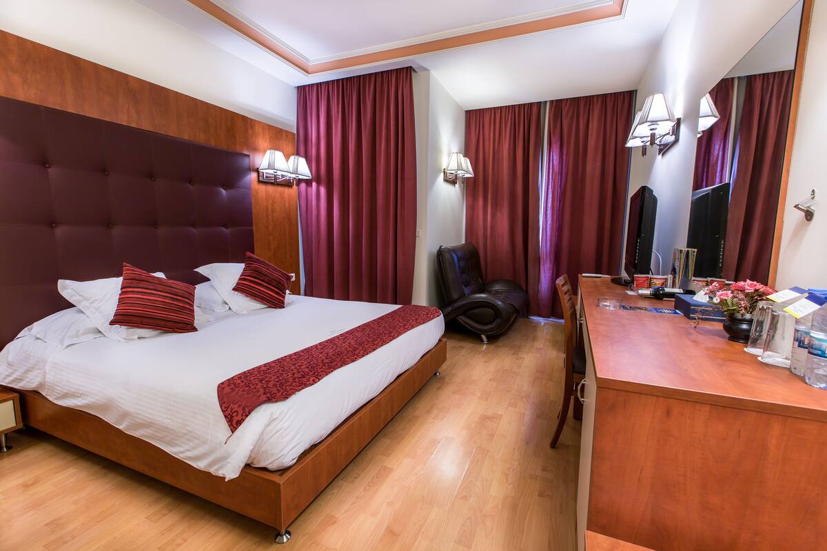 A hotel room with a large bed, a desk, and a chair.