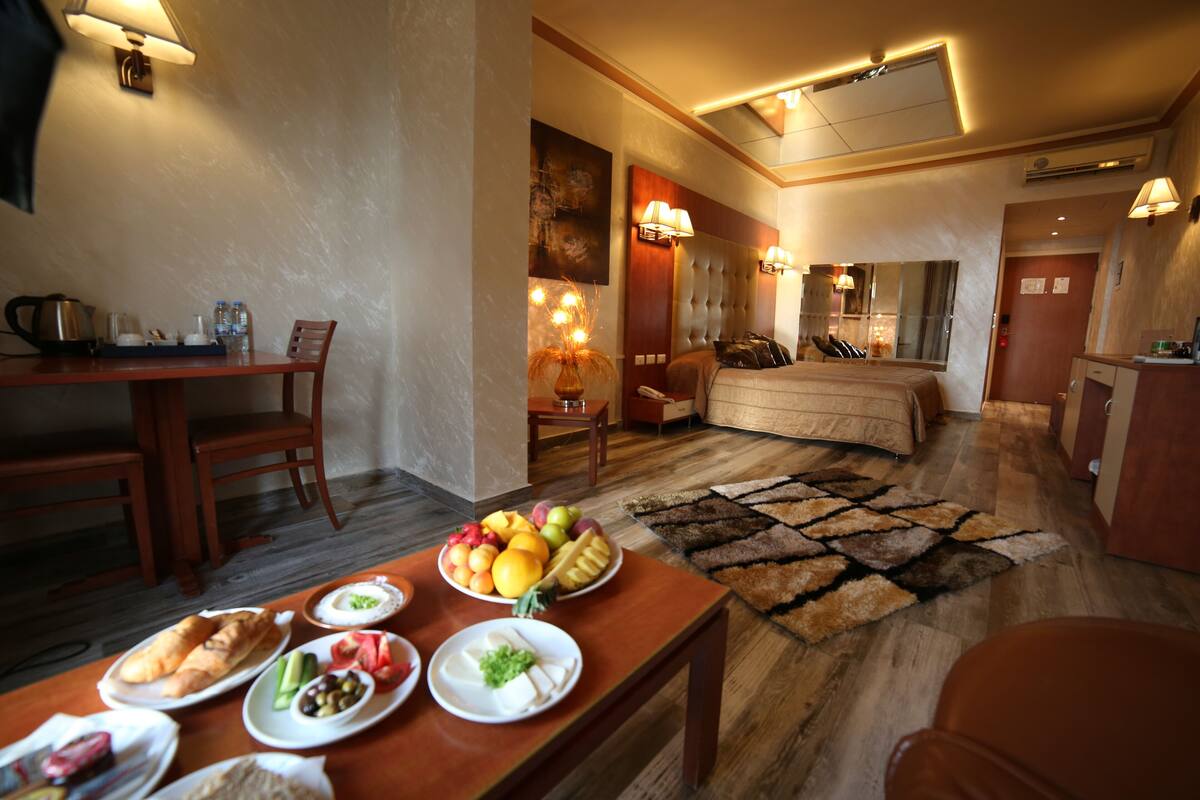 A hotel room with a dining area, a bed, and a small kitchenette.