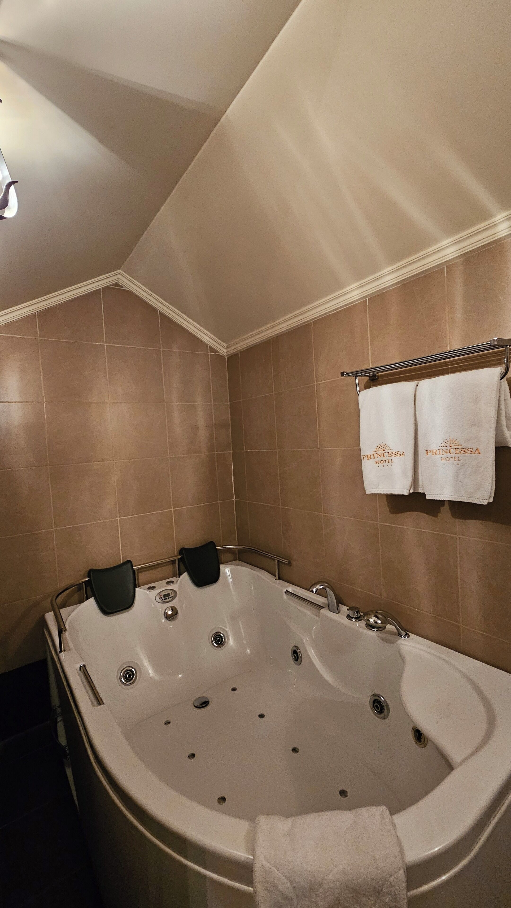 Un baño con una bañera grande, un perchero con dos toallas y una zona de ducha.